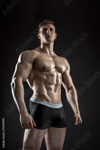 Muscular bodybuilder guy doing posing over black background