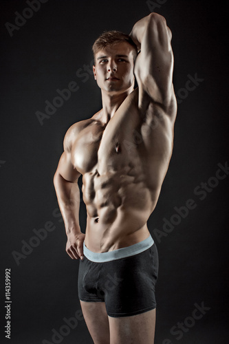 Muscular bodybuilder guy doing posing over black background © nazarovsergey