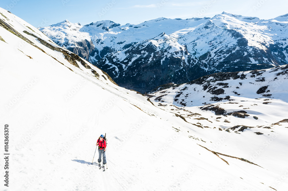 Female skier ascending a mountain slope.