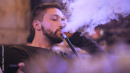 handsome man smokes hookah in the bar