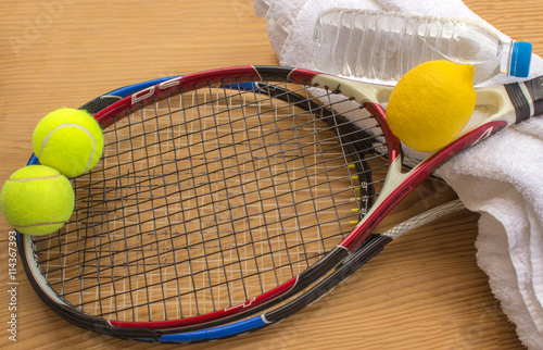  Tennis rackets and balls are next to a bottle of water and lemo © 008melisa