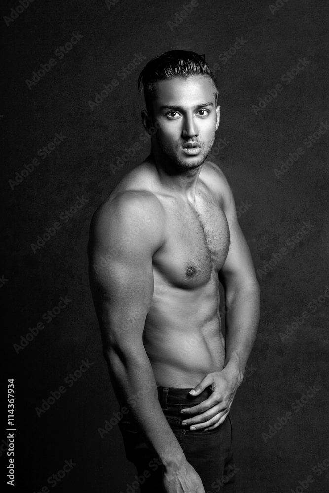 Fototapeta premium Sexy shirtless male model flirting against black background