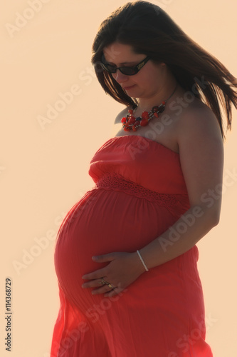 Beautiful pregnant woman in red dress,holding the belly