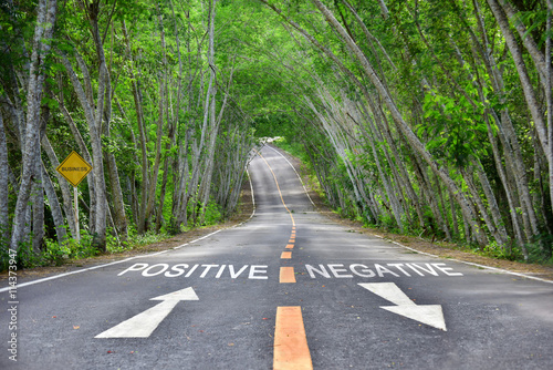 Words of positive and negative with white arrow and yellow line marking on road surface