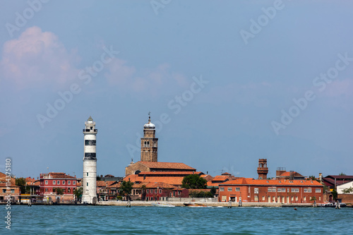 Faro di Murano Lighthouse on the Venetian island of Murano, a round cylindrical stone tower with three black horizontal bars near the top, built in 1912.