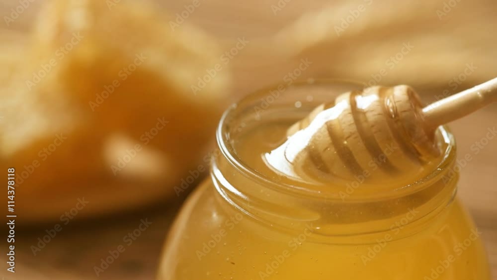 Honey in jar with honey dipper on wooden background Honey in jar with honey dipper on wooden background