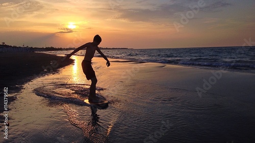 boy on surf at sunset © oscar