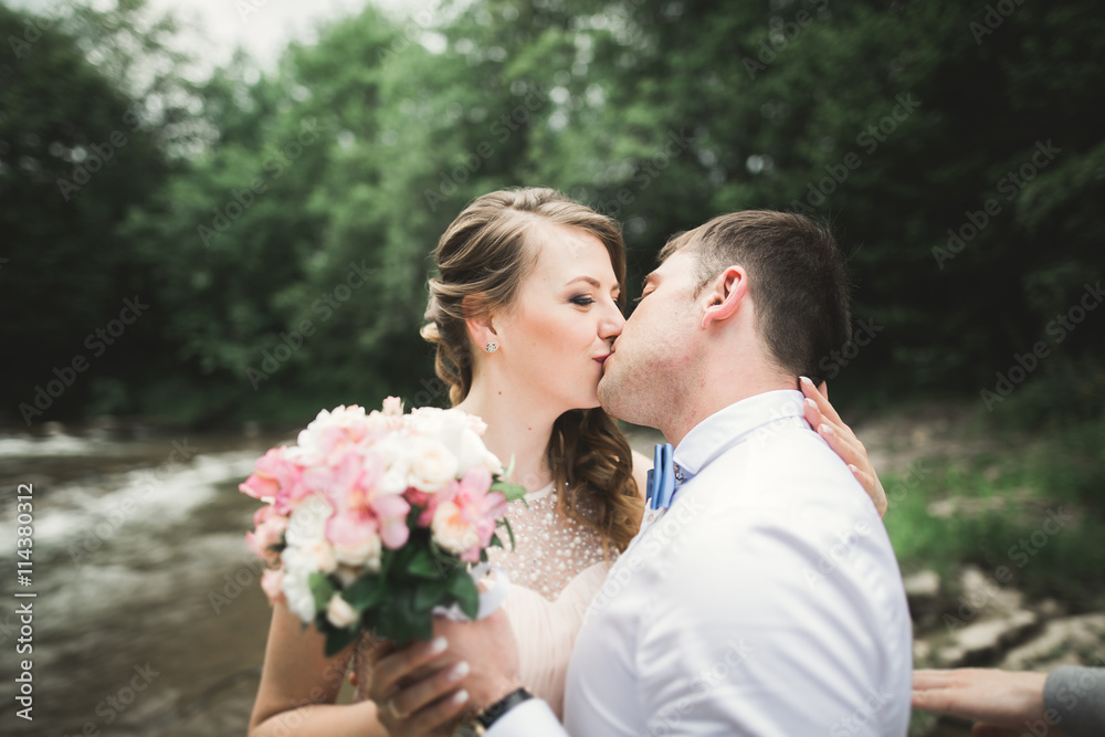 Elegant gentle stylish groom and bride near river with stones. Wedding couple in love Elegant gentle stylish groom and bride near river with stones. Wedding couple in love