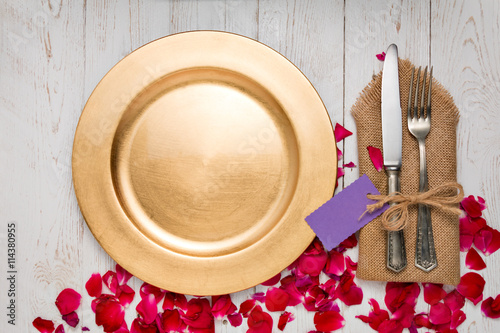 Silverware with an empty tag on a table with an gold plate