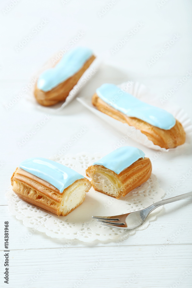 Eclairs with glaze on a white wooden table Eclairs with glaze on a white wooden table