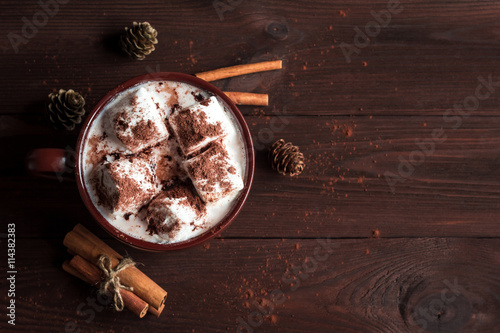Hot chocolate in a mug, marshmallows, cinnamon sticks and fir cones, top view, flat lay