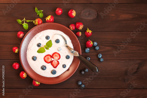 Healthy yogurt with strawberry and blueberyy on wooden background. Rustic food. Flat lay, top view photo