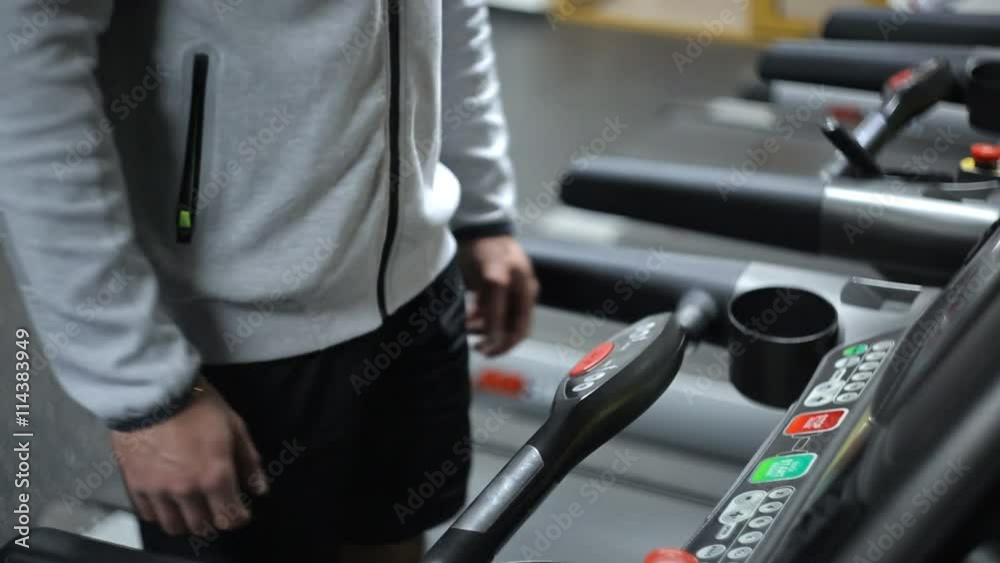 A man in shorts and a sweatshirt is engaged on a treadmill, increasing pace. A man in shorts and a sweatshirt is engaged on a treadmill, increasing pace.