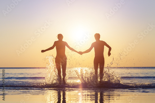 Happy couple running to the sea with splashes of water
