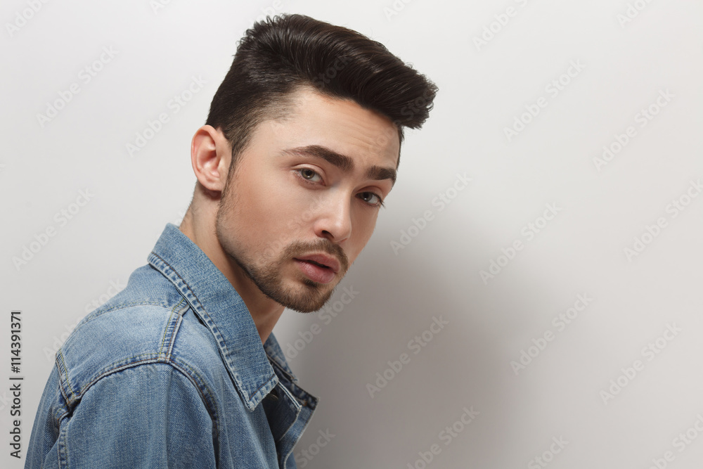 Closeup portrait of young model man in jeans shirt over white background.  Handsome man with modern hairstyle in studio. Stock Photo | Adobe Stock