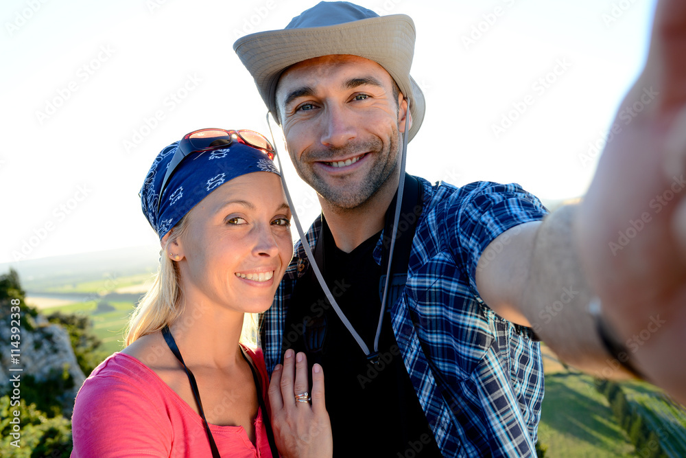 young couple on a hiking adventure trek making selfie with beautiful sunset landscape