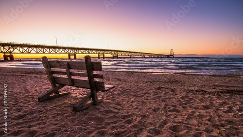 Mackinaw Bridge Twilight.. Park bench on the shores of the Mackinac Straits with the Mackinaw Bridge at the horizon. photo