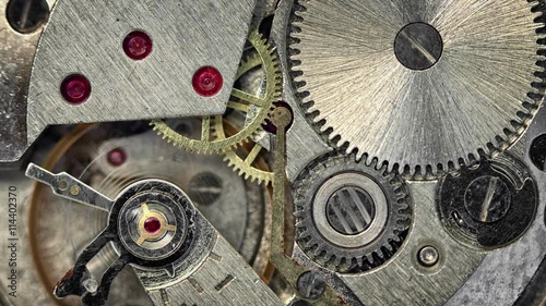 Video 3840x2160 - Clockspring, flywheel and continuous gears comprise the clockwork mechanism that drives a watch. This closeup view demonstrates the physics involved. photo