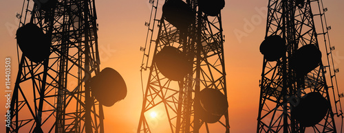 Silhouette, telecommunication towers with TV antennas and satellite dish in sunset, panorama composition photo