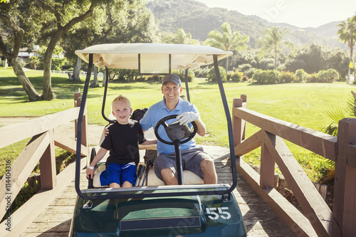 Father and son golfing together on a Summer day riding in a golf cart together