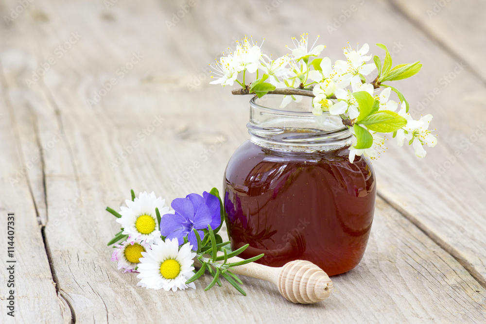 Honey in jar, flowers and honey dipper on wooden background Honey in jar, flowers and honey dipper on wooden background