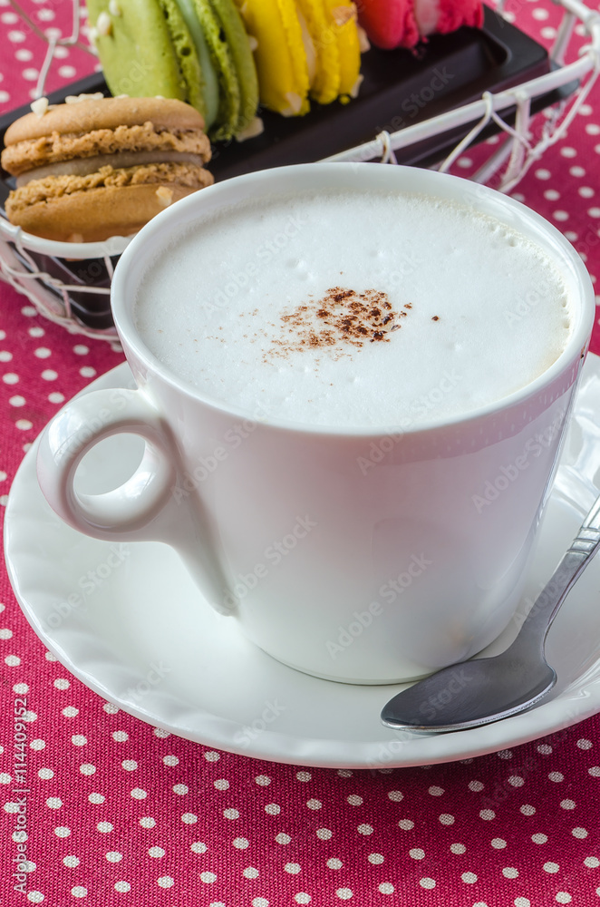 White cup of fresh cappuccino and sweet macaroons for morning c White cup of fresh cappuccino and sweet macaroons for morning c