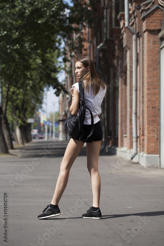 Young beautiful woman in a blue dress walking on the summer stre