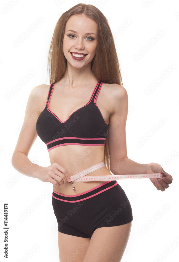 Fit and healthy young lady measuring her waist with a tape measure in centimeters and millimeters