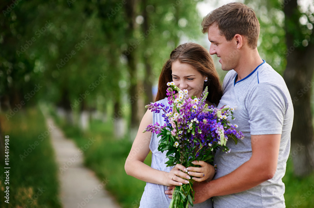 beautiful couple in love walking with a bouquet of wildflowers