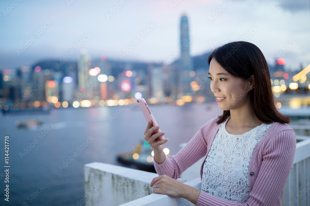 Woman hold with cellphone in Hong Kong at night
