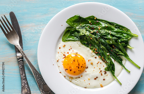 Fried egg with spinach on the wooden table