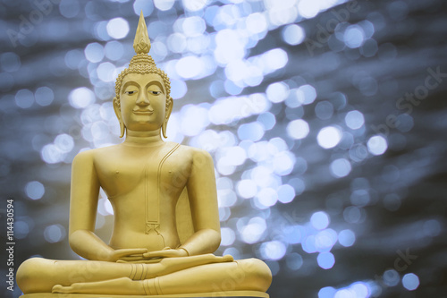 Gold image of Buddha on blurred light bokeh background, copy space, filtered image