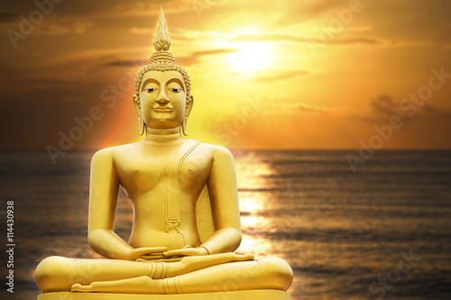 Gold image of Buddha in Blurred sunrise or sunset moment , with seascape, light effect added in back of image of buddha, prachuapkhirikhan,thailand,filtered image