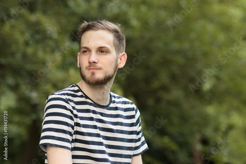 Young man looking sideways outdoors Upper body shot
