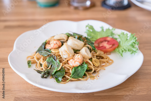 spicy spaghetti seafood with chicken on wood table. Thai style