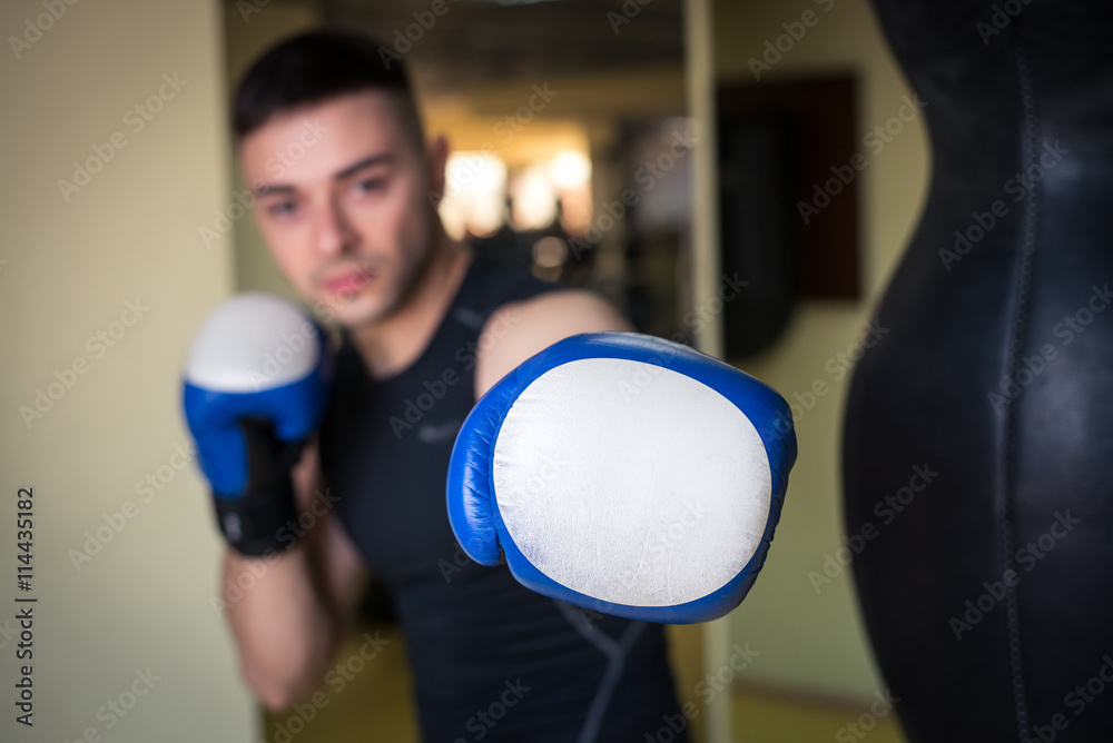 Portrait of young male boxer training in gym.