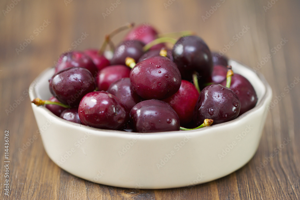 cherries in dish on dark brown wooden background cherries in dish on dark brown wooden background