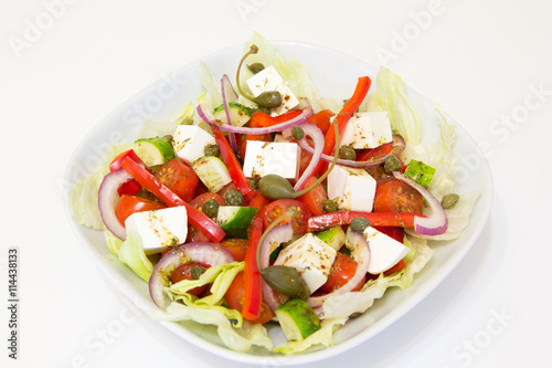 Греческий салат с каперсами на белой тарелке