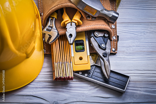 Protective hard hat tool belt on wooden board construction conce