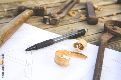 Sketch, pencil and old rusty tools on wooden table