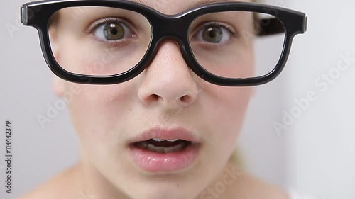 young girl with nerd glasses pointing with the finger to the side
