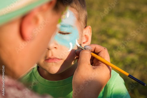 Woman does greasepaint on the child's face