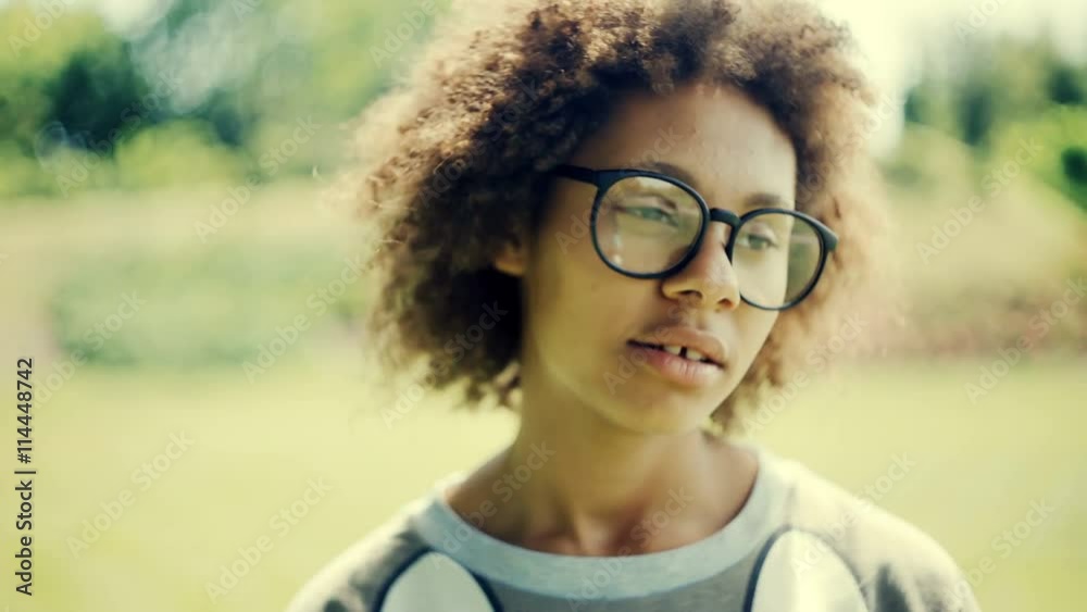 Young pensive beautiful woman with glasses closeup simulates happiness. Park, summer sunny day.