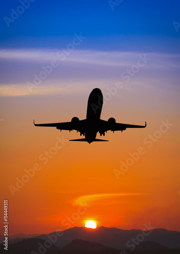 Silhouette of plane fly over the mountain during sunset.