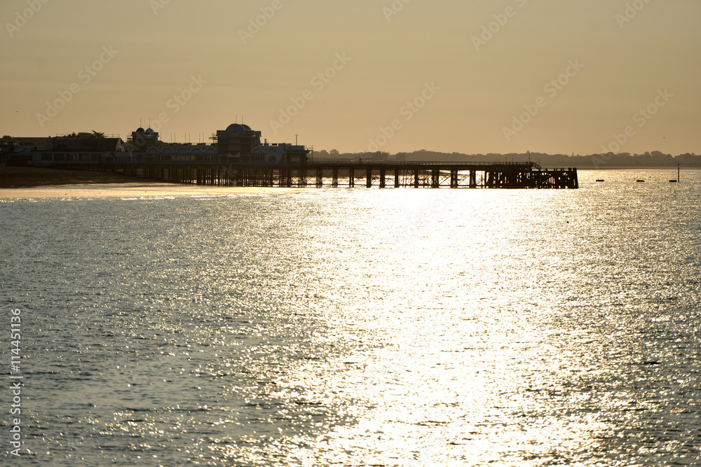Sunset behind a pier with calm sea