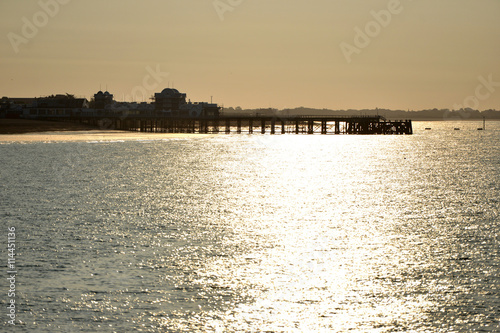 Sunset behind a pier with calm sea