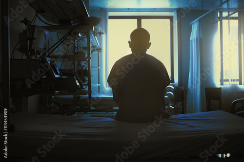 Figure of sitting patient on a hospital bed on the background of photo