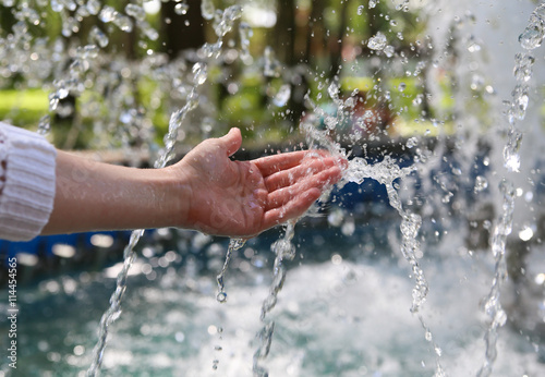 Hand touches clean and fresh water from the fountain.