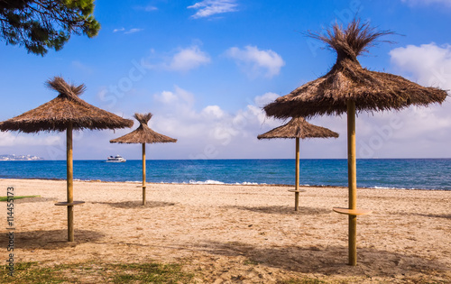 Fototapeta Naklejka Na Ścianę i Meble -  Lonely beach, straw sunshades, sea, blue sky and touristic speed
