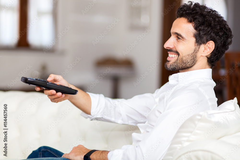 Fototapeta premium Man on the couch switches remote control TV channels